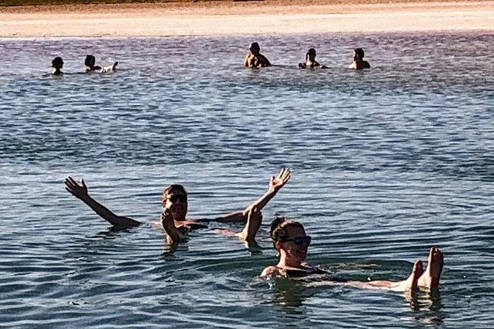 People float effortlessly in a shallow, clear lagoon under the sun.